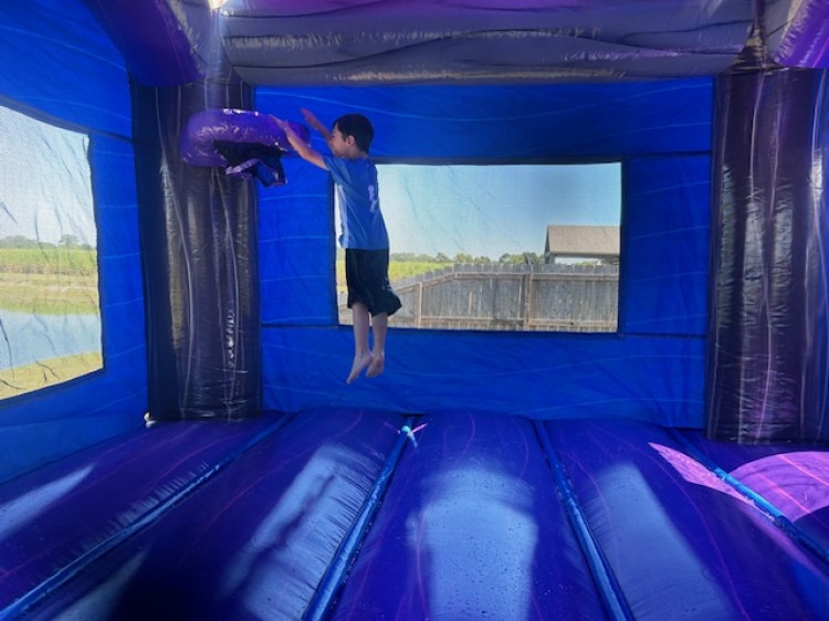 Child jumping inside a bounce house with basketball hoop at a birthday party rental