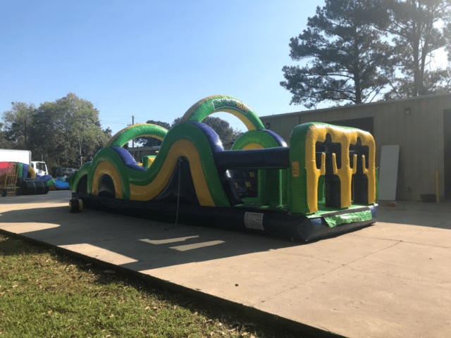 Green inflatable obstacle course rental set up in a driveway for a church event