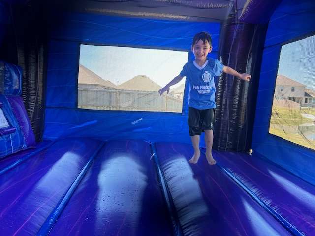 Child playing inside a blue bounce house rental at a birthday party