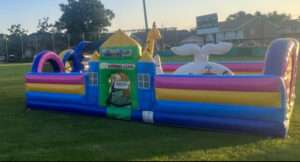 Inflatable toddler playland and bounce house units set up on a grass field at a community event in Acadiana, Louisiana