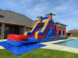 Tall inflatable water slide rental with splash pool set up in a backyard