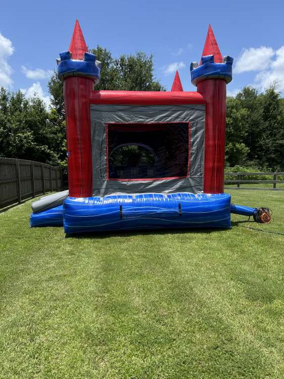 Red blue and gray marble castle bounce house with turret towers set up front-on on a green lawn, a compact walled unit that also fits indoor venues in Acadiana