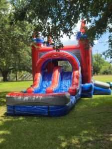 Red white and blue bounce house and water slide combo rental on green grass in Lafayette Louisiana