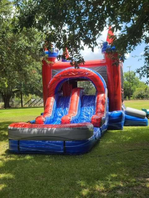 Red white and blue bounce house and water slide combo rental on green grass in Lafayette Louisiana