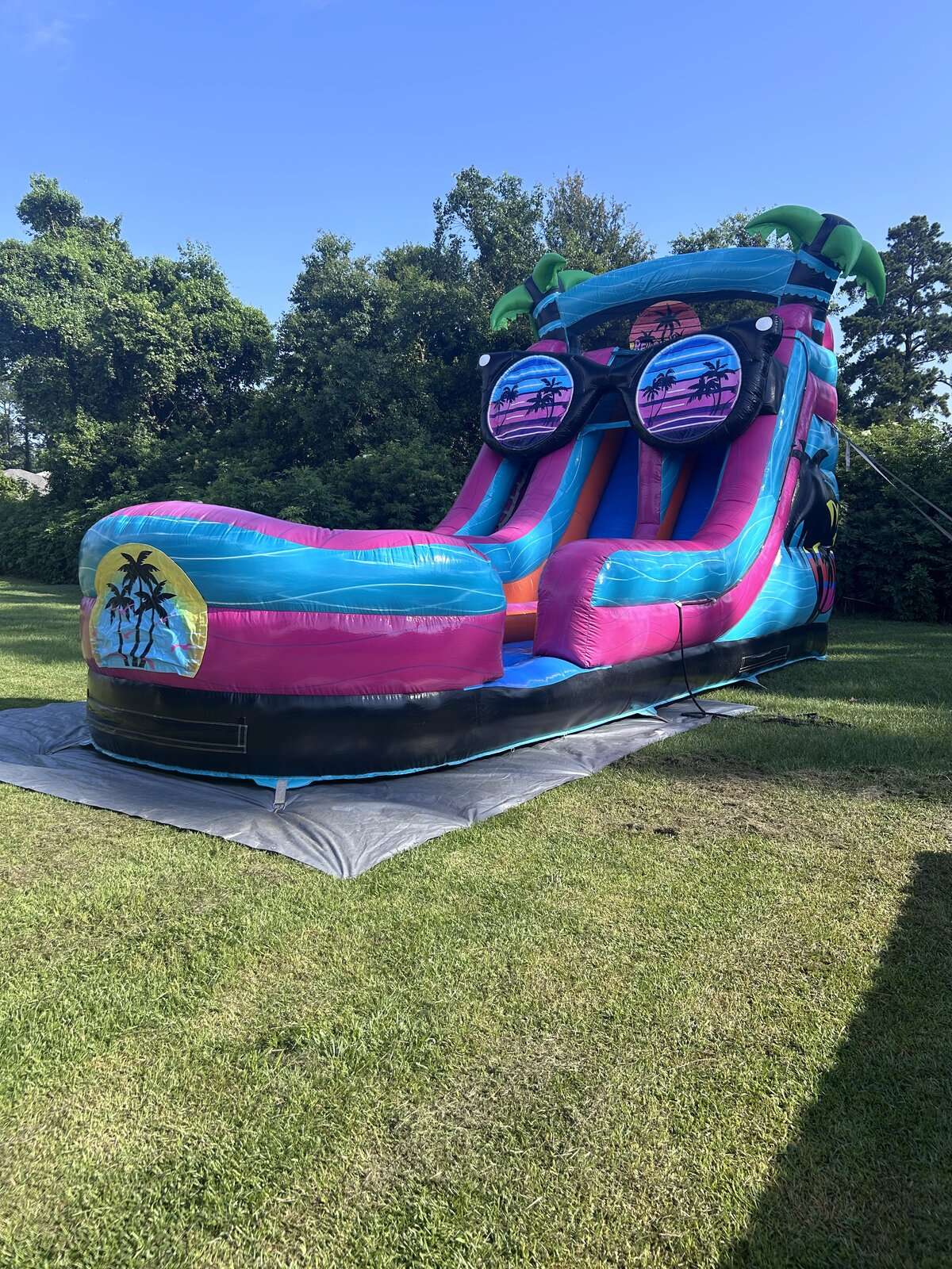 Bright pink and blue tropical water slide rental set up in a yard for an Acadiana neighborhood block party in Lafayette, Louisiana
