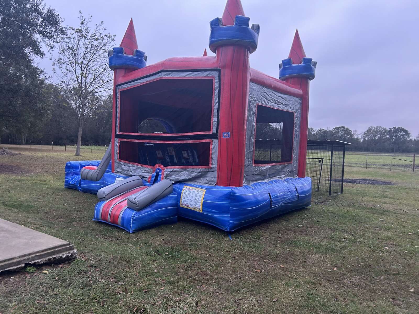 Red and blue castle bounce house combo rental set up dry on grass in an open Maurice, LA yard