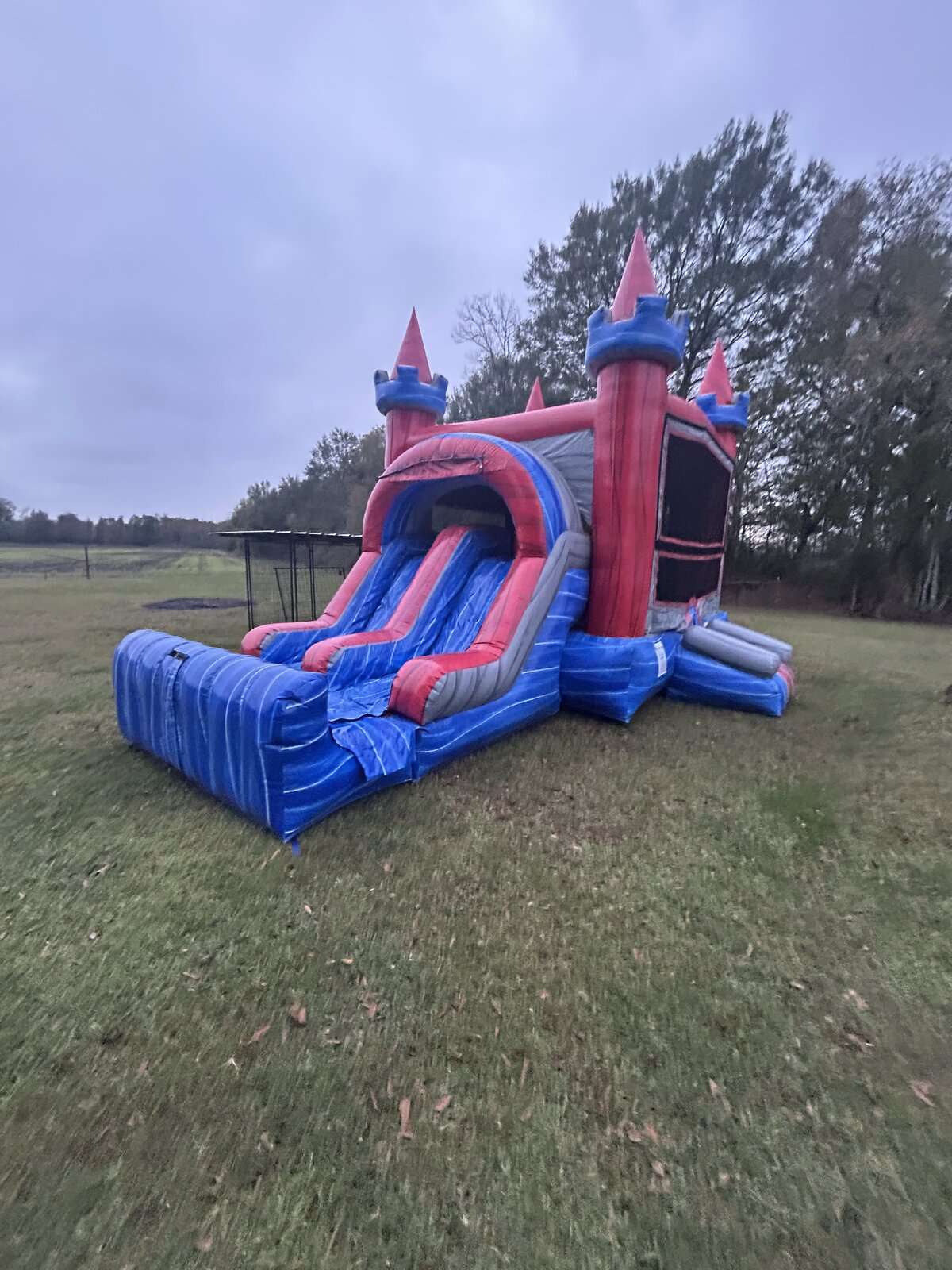 Red and blue castle bounce house and dry slide combo rental set up in an open field near Maurice, Louisiana