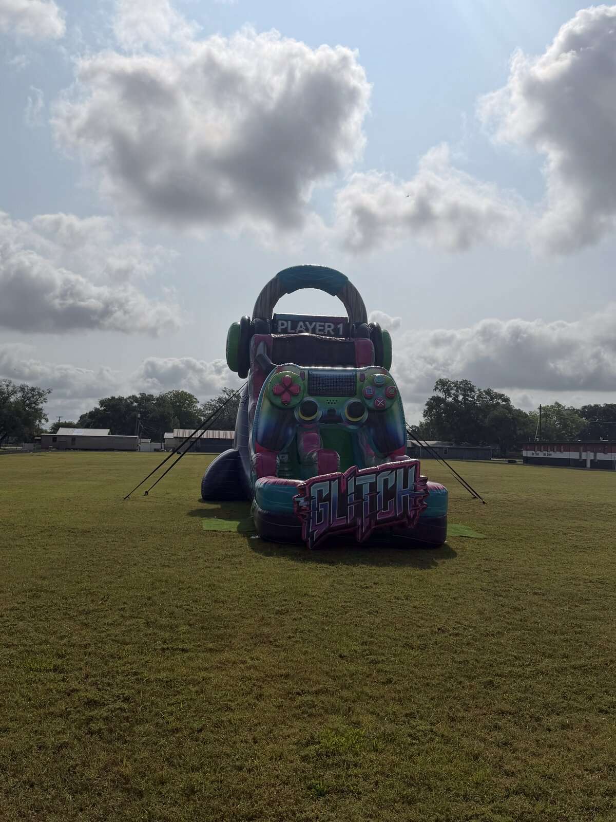 GLITCH gamer-themed inflatable slide staked down on an open ballfield, ready for a game-day party in Acadiana