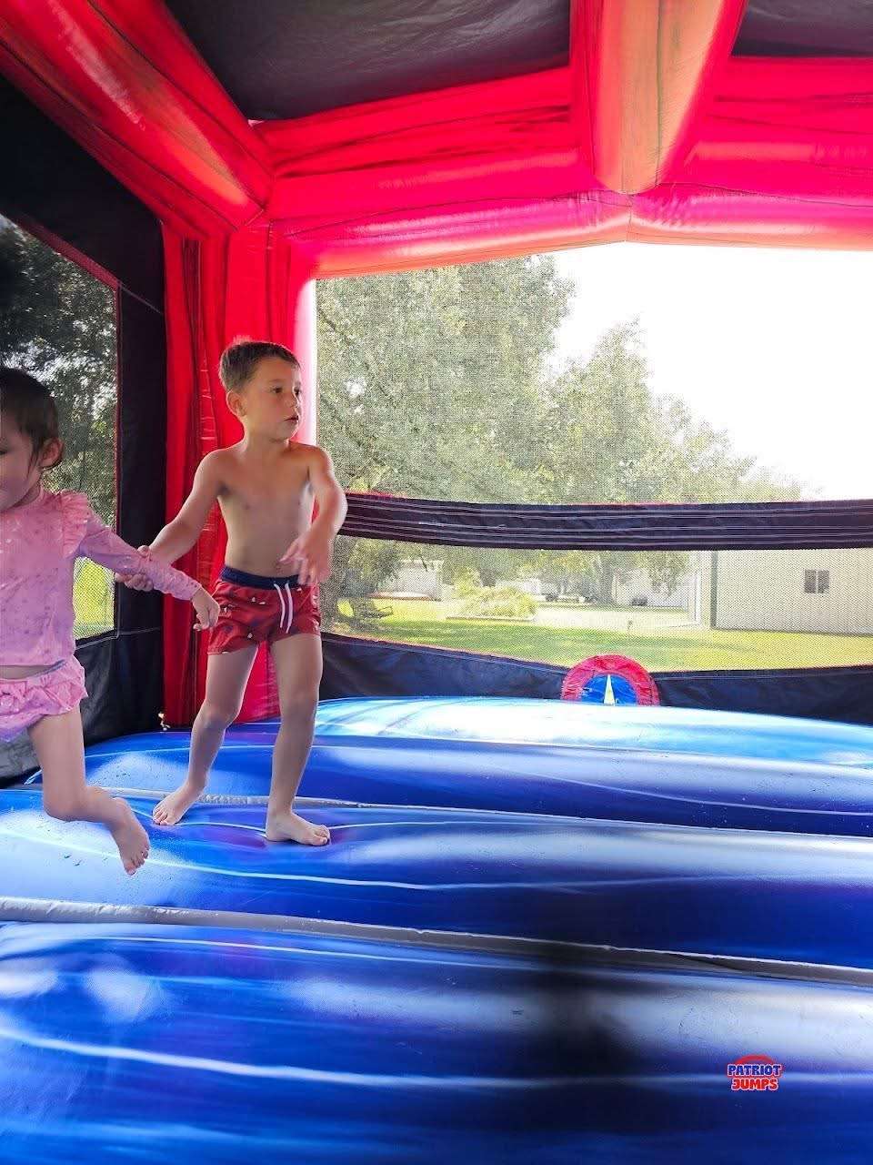 Kids jumping inside a red and blue bounce house rental in an Acadiana backyard