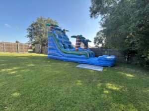 Blue tropical water slide rental set up in a sunny Acadiana backyard for a Labor Day weekend party