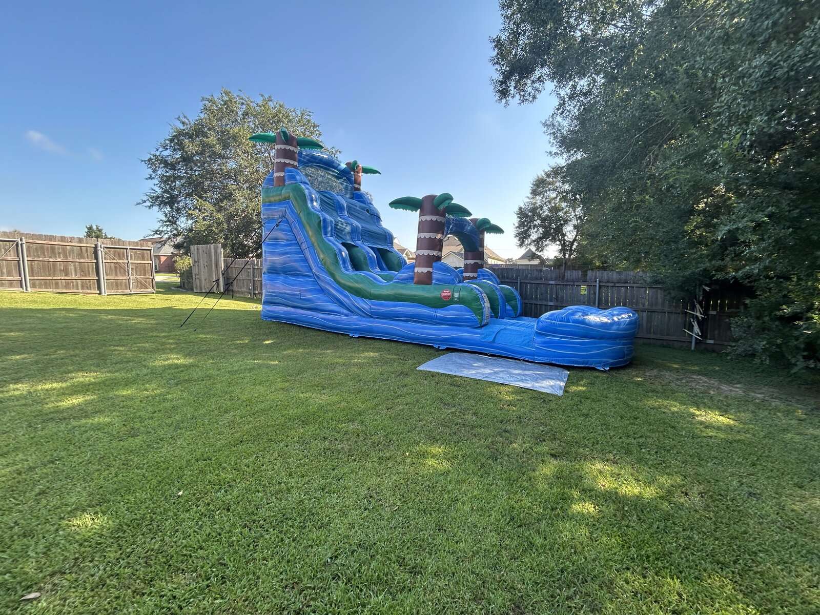 Blue tropical water slide rental set up in a sunny Acadiana backyard for a Labor Day weekend party