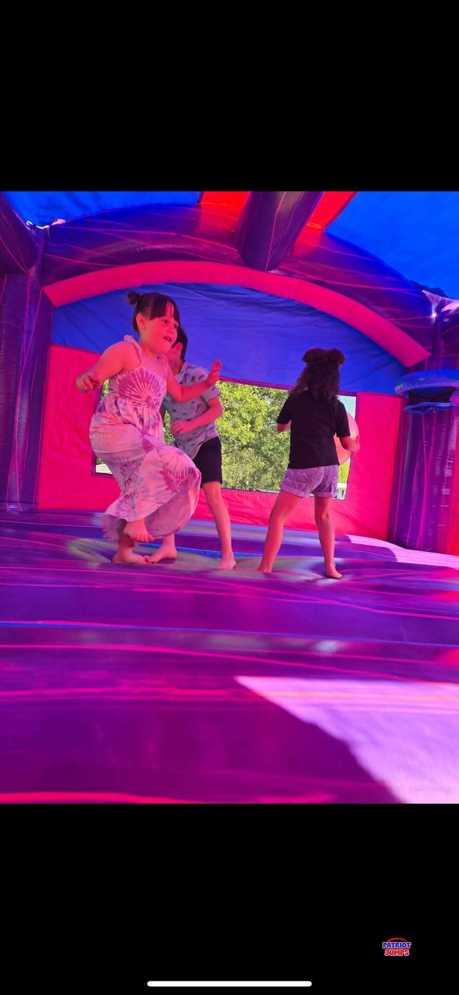 Three children playing barefoot inside a clean, sanitized bounce house interior at an Acadiana party