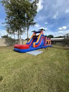 Inflatable water slide with splash pool set up on grass at an Acadiana summer party, keeping kids cool in the heat