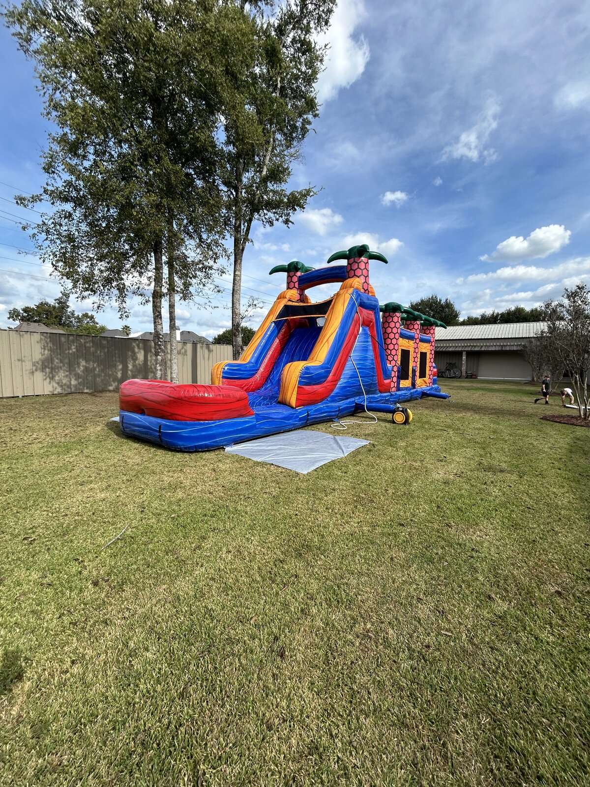 Inflatable water slide with splash pool set up on grass at an Acadiana summer party, keeping kids cool in the heat