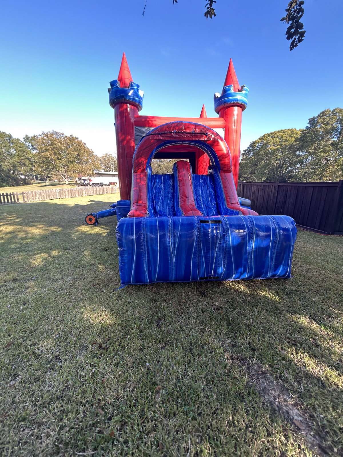Red and blue castle water slide combo rental set up on open grass, ideal for a park or open-space party in Acadiana