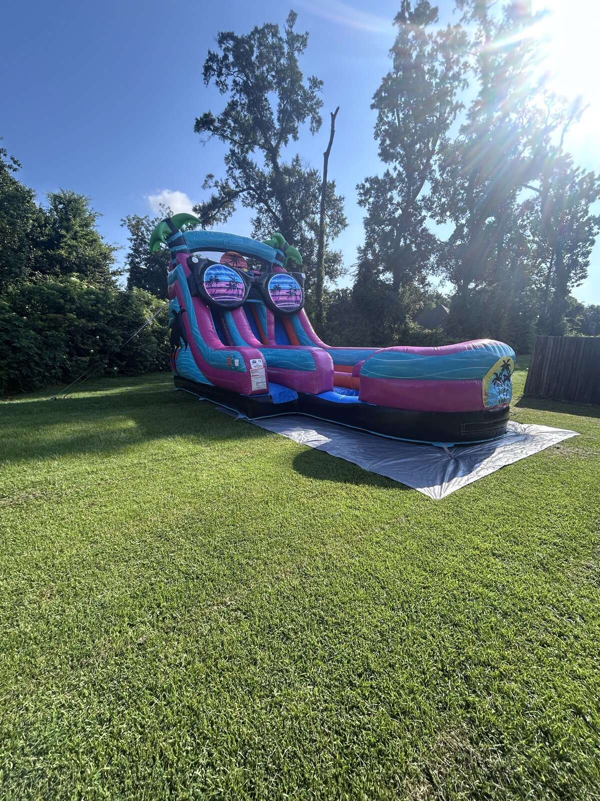 Pink and teal tropical water slide rental set up dry in an Acadiana backyard for a budget-friendly party