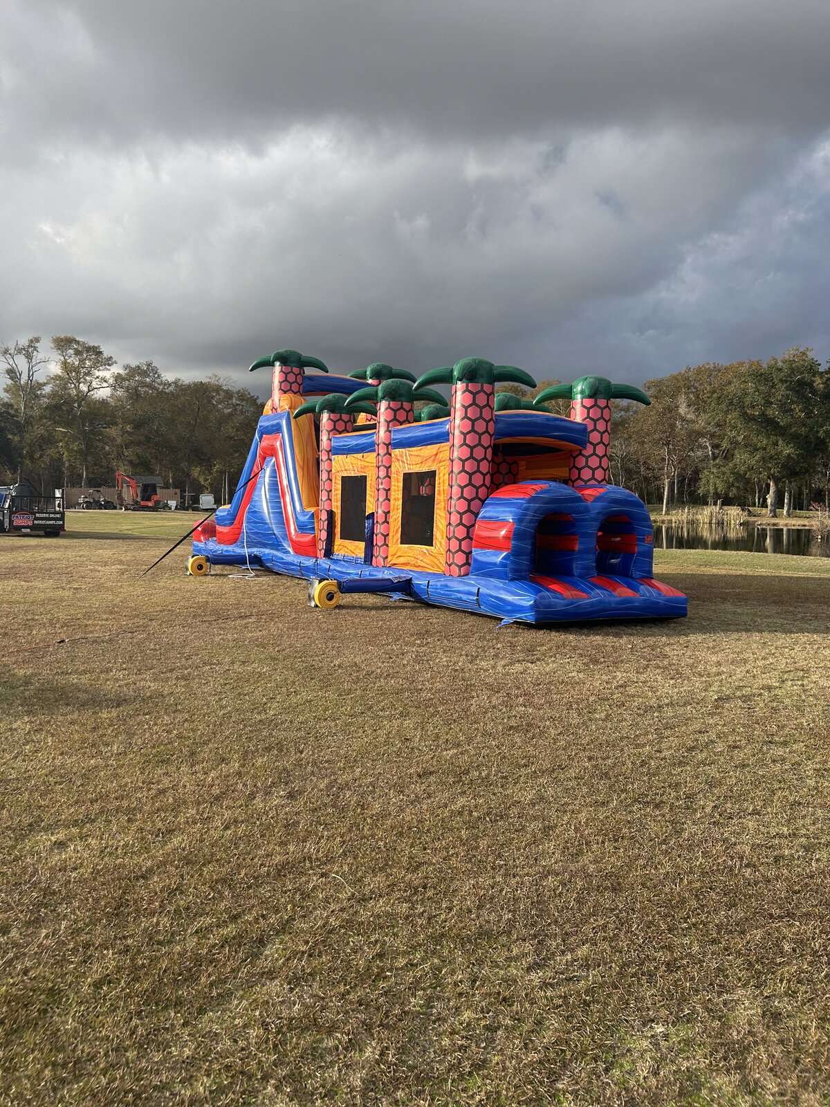 Long inflatable obstacle course rental with tunnels, climbs and a slide staged at a ball field in Lafayette, LA