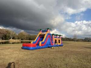 Inflatable tropical obstacle course and slide rental set up in a wide open field for a youth sports team party in Acadiana