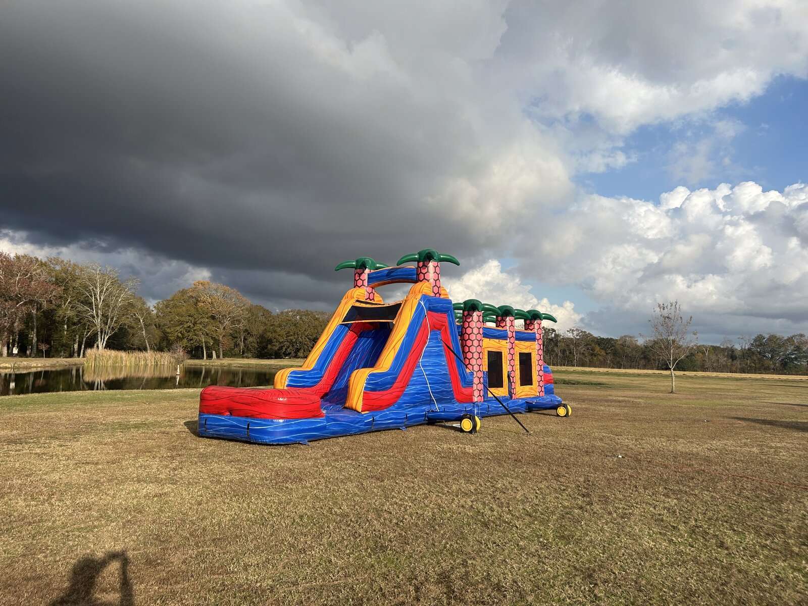 Inflatable tropical obstacle course and slide rental set up in a wide open field for a youth sports team party in Acadiana