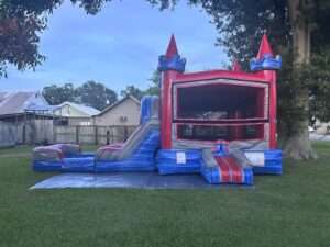 Red and blue castle bounce house and slide combo set up at dusk for a weekend rental in Acadiana
