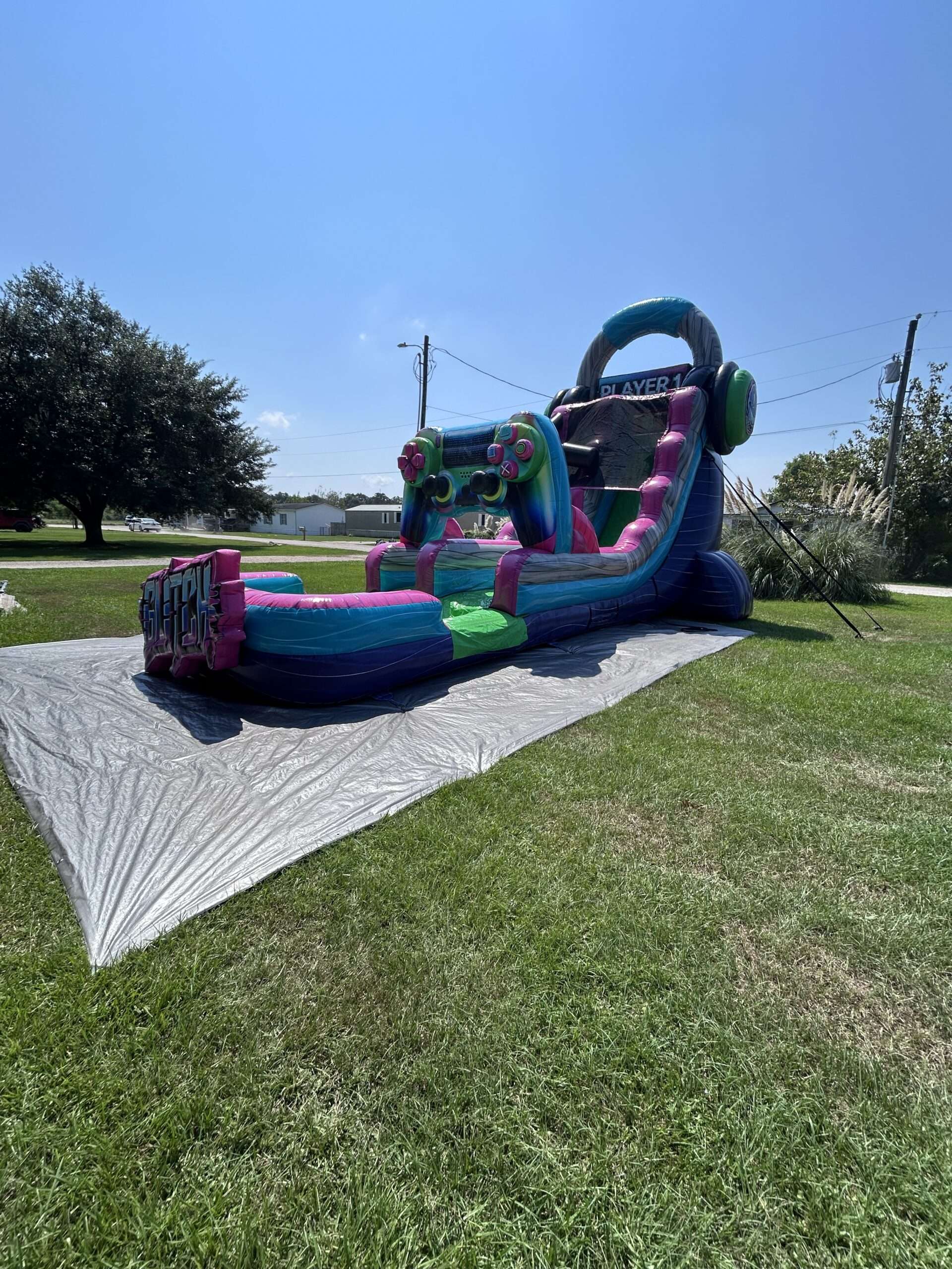 Teal and pink inflatable slide set up on a front lawn for a holiday party in Youngsville, LA