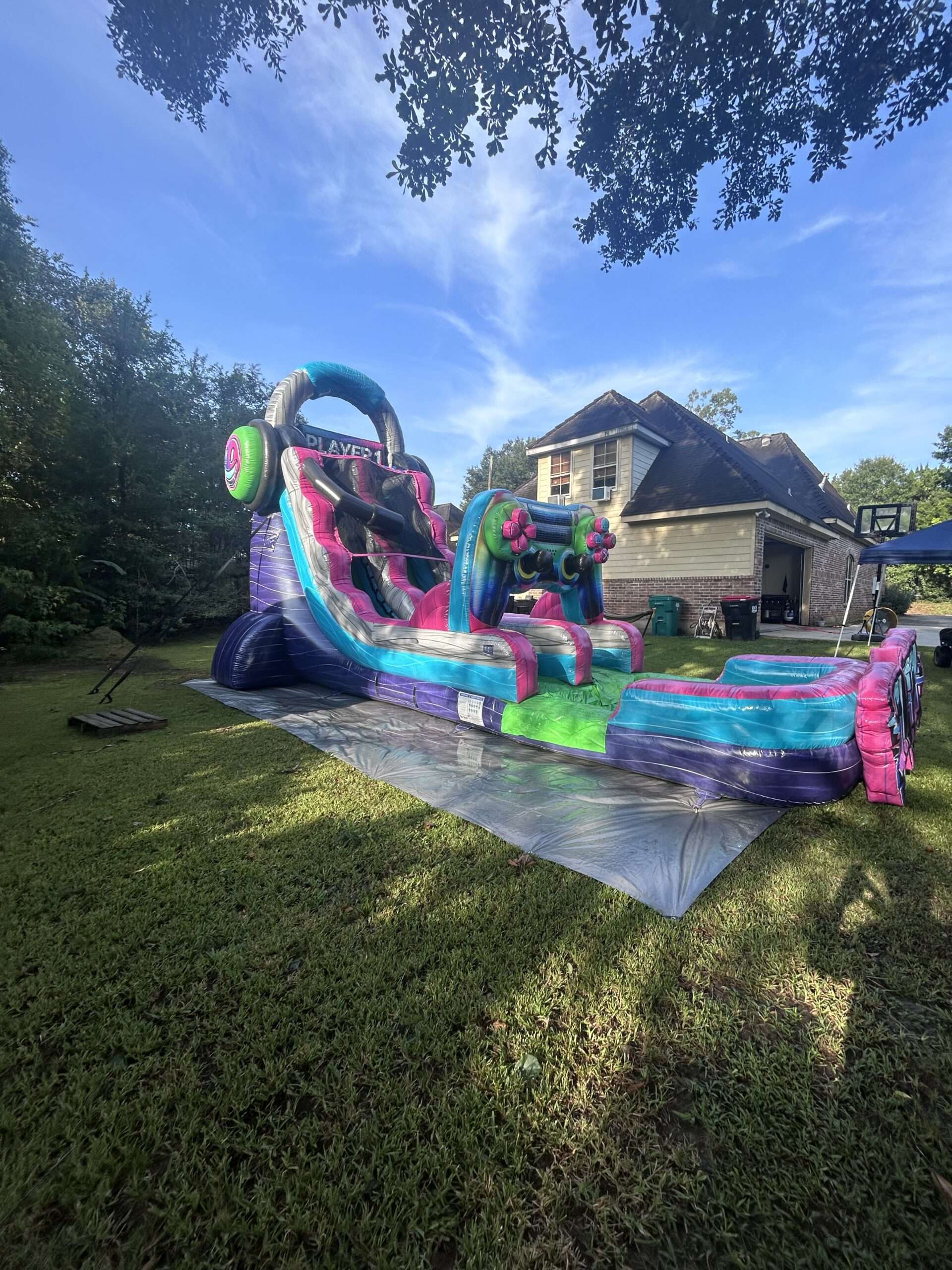 Pink and teal inflatable slide set up on a front lawn for a family party in Lafayette, LA